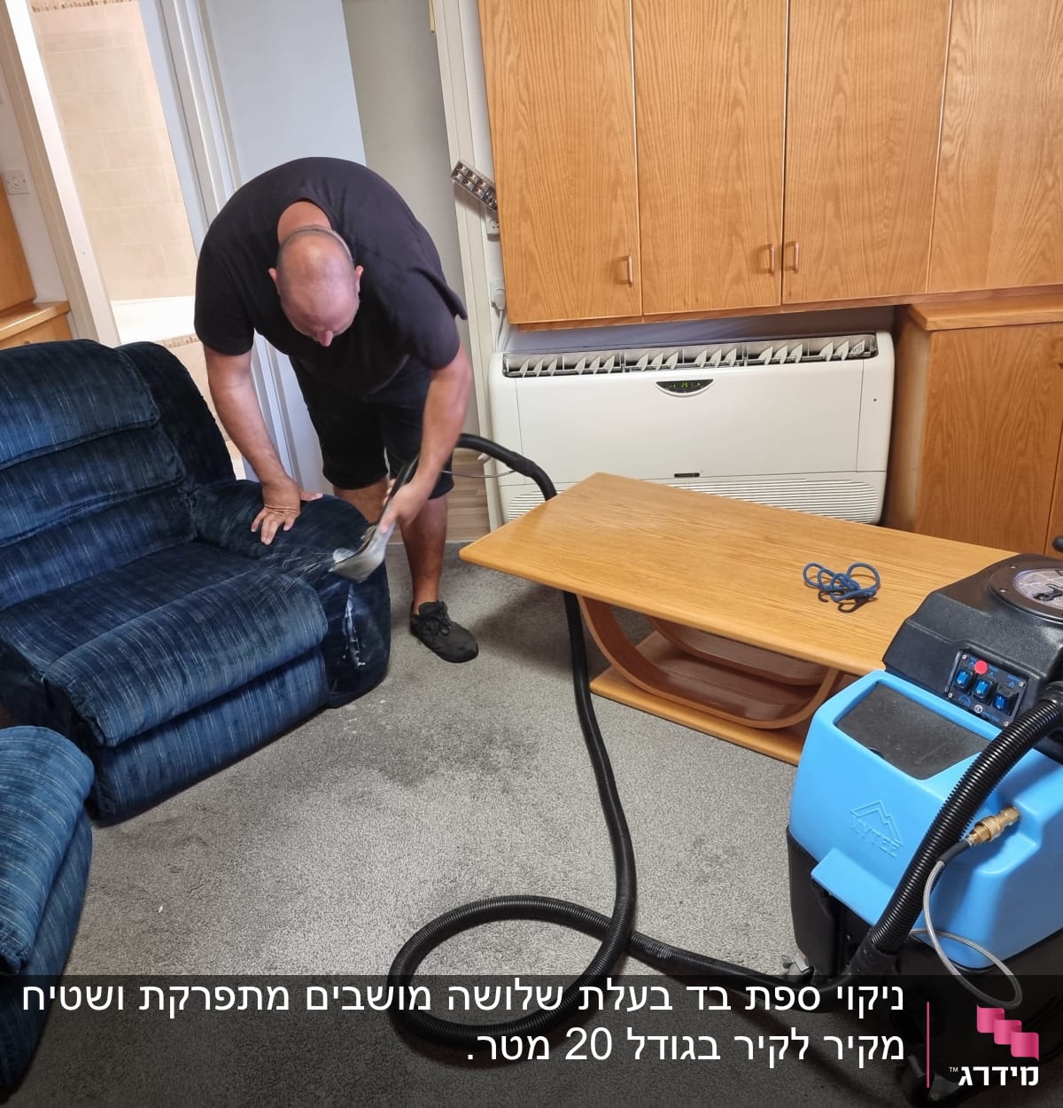 אדם מנקה ספה עם מכונת ניקוי מקצועית